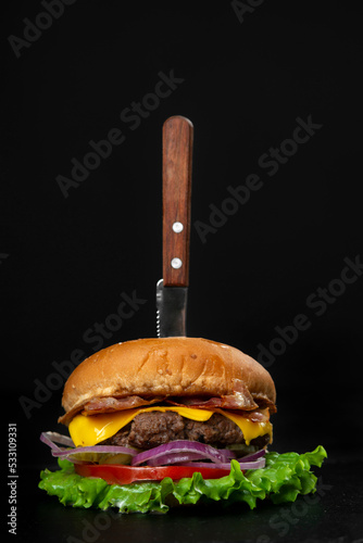Burger served with knife on black copy space background