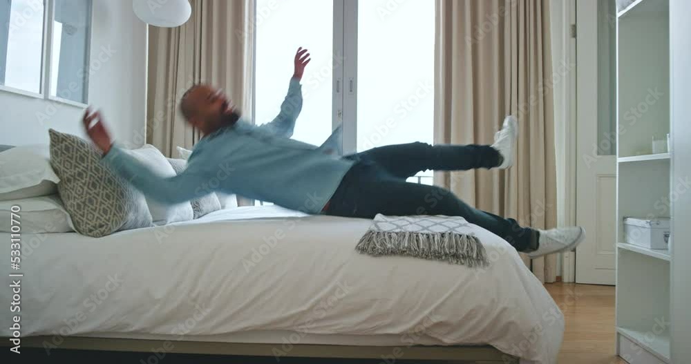 Luxury, hospitality and relax man jump on bed in hotel or home room during vacation. Happy, smile and young male tired, lazy and smile in bedroom while relaxing in apartment or house during holiday