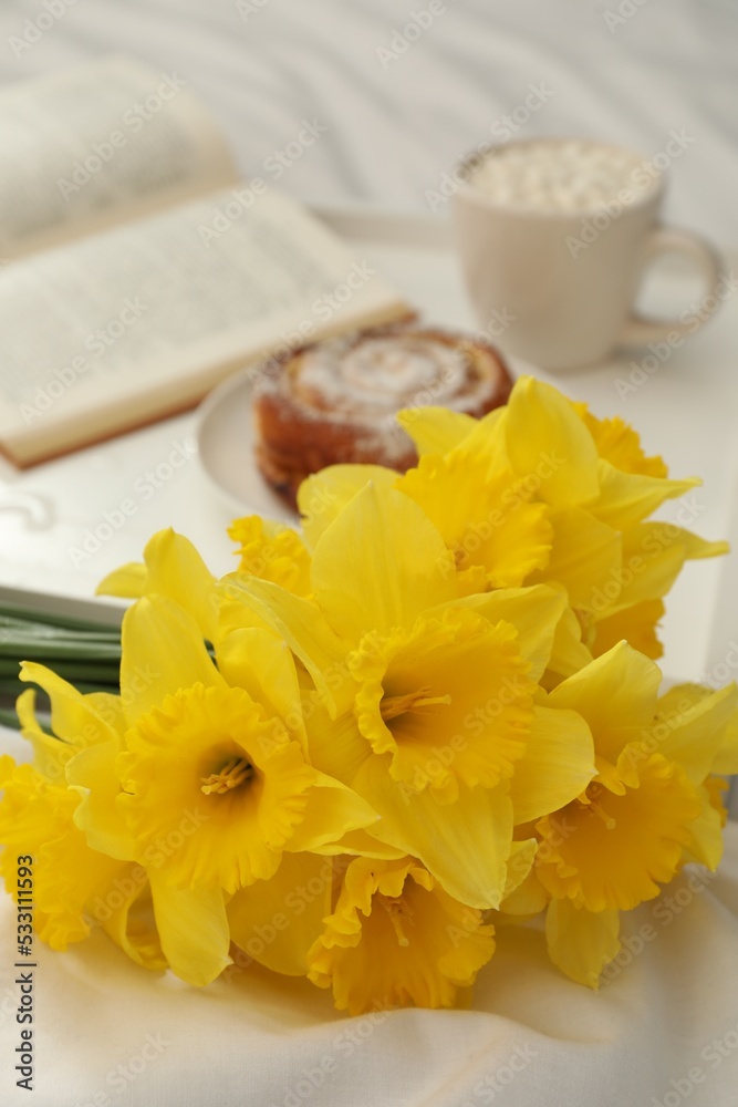 Bouquet of beautiful daffodils on white bed, closeup