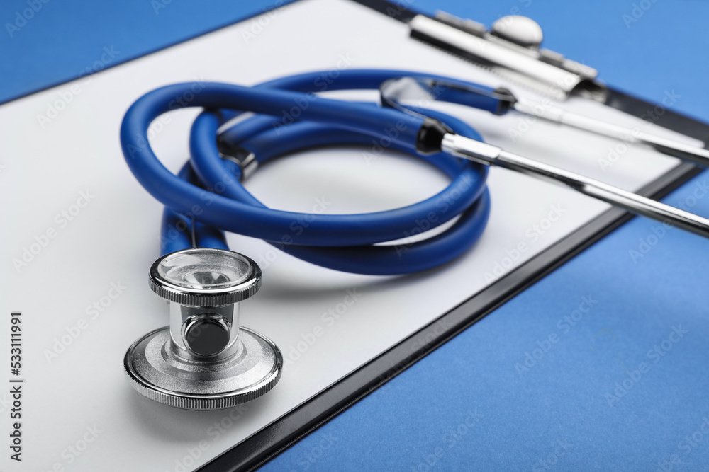 Clipboard with stethoscope on blue background, closeup Clipboard with stethoscope on blue background, closeup