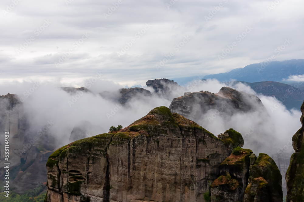 Scenic view of unique rock formations near Holy Monastery of Varlaam on cloudy moody day in Kalambaka, Meteora, Thessaly, Greece, Europe. Rocks overgrown with moss, misty fog coming up from valley