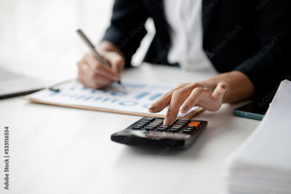 Businessman using a calculator to calculate numbers on a company's financial documents, he is analyzing historical financial data to plan how to grow the company. Financial concept. Businessman using a calculator to calculate numbers on a company's financial documents, he is analyzing historical financial data to plan how to grow the company. Financial concept.