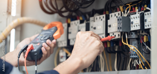 Electrician engineer work tester measuring voltage and current of power electric line in electrical cabinet control   concept check the operation of the electrical system .