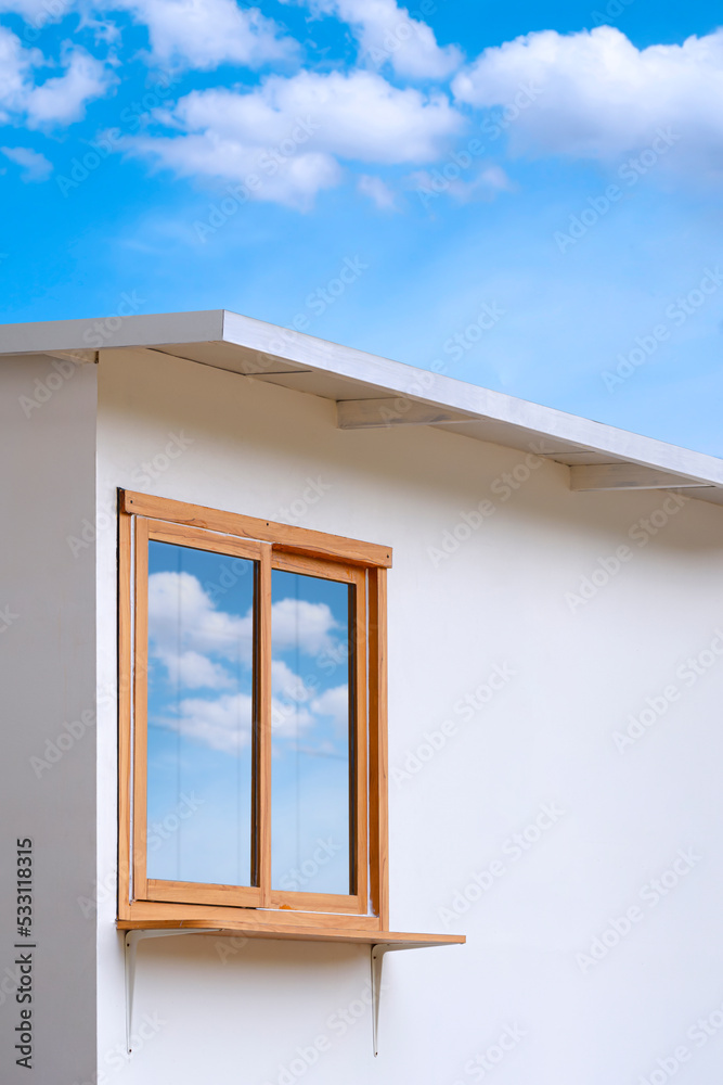 Glass and wooden window on white wall of mini street coffee kiosk outside of shopping mall against cloud on blue sky in vertical frame