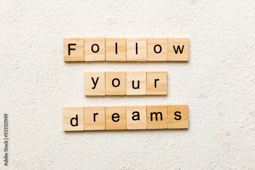 Follow your dreams word written on wood block. Follow your dreams text on cement table for your desing, Top view concept