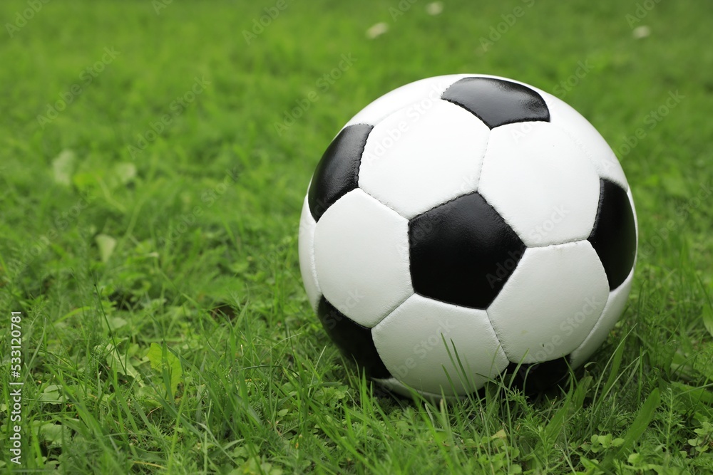 Soccer ball on green grass outdoors, space for text