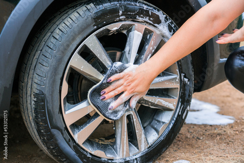 A woman's hand washes a car wheel, close-up