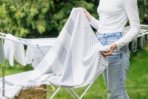 фотографія woman hanging clean clothes on drying rack outside