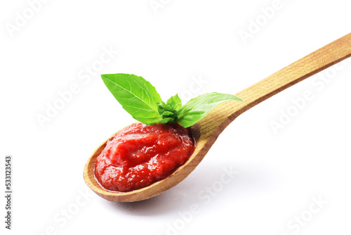 Wooden spoon full of tomato sauce with fresh basil isolated on white background.