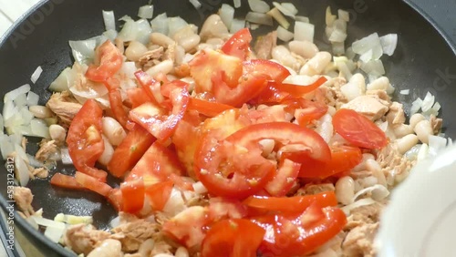 Frying onion, garlic and tomatoes in the pan. Preparing the food in the pan to make dinner