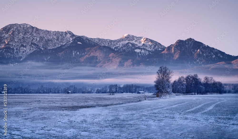Gefrorene Landschaft mit Bergen und Feldern im nebligen Morgenlicht an einem kalten Wintertag - Postkartenmotiv