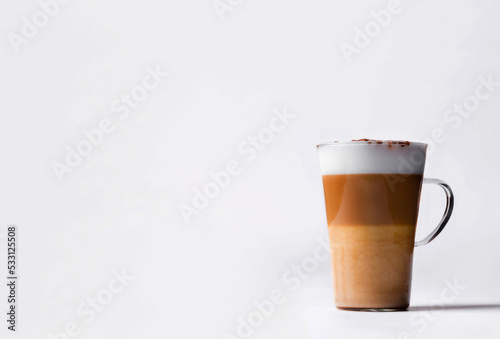 Milk coffee or latte macchiato glass, on white background. Italian coffee with milk and layers. Gourmet coffee.