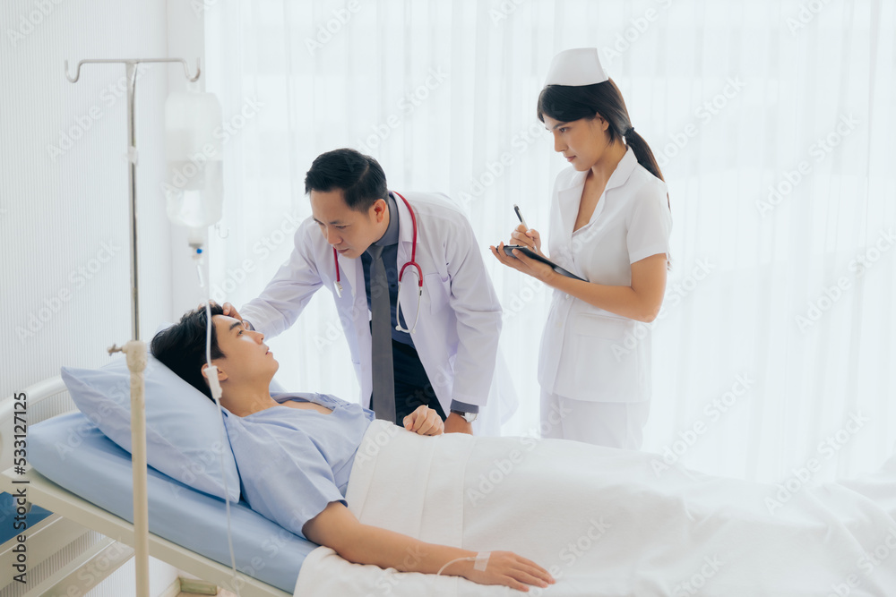Obraz premium Doctor and nurse visiting and using stethoscope checking examine heartbeat male patient at hospital