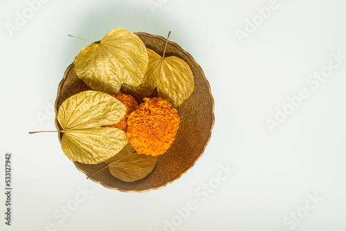 Symbolic golden leaves with marigold flowers in the bowl for the Dussehra occasion. Objects for Hindu festival ‘Vijayadashami’ or ‘Dashahara’ celebration. photo