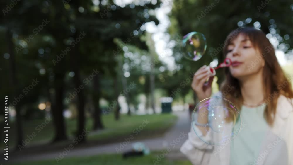 Girl inflates soap bubbles outdoor in park. Golden hour sunset light. Beautiful caucasian young girl. Girl inflates soap bubbles outdoor in park. Golden hour sunset light. Beautiful caucasian young girl.