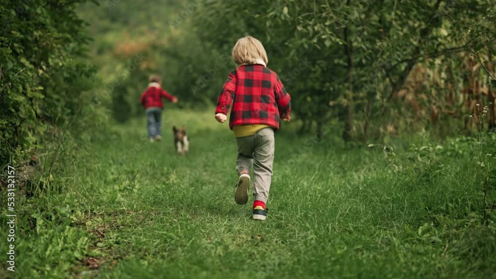Happy kids running together with beagle puppy in green garden. Smiling brothers, stylish boys having fun with dog, playing outdoors. Friendship, family, twins, childhood concept Happy kids running together with beagle puppy in green garden. Smiling brothers, stylish boys having fun with dog, playing outdoors. Friendship, family, twins, childhood concept