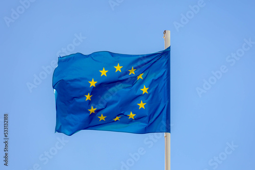 The flag of Europe on the pole waving in the air with blue sky as background, European union flag consists of twelve golden stars forming a circle on a blue field, A symbol for the whole of Europe.