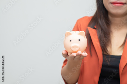 business woman hold piggy bank and putting coin with concrete wall for financial and saving money concept with concrete background and blank copy space.