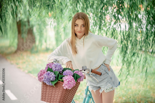 beautiful fair-haired girl on a bicycle with flowers. Hydrangeas.
