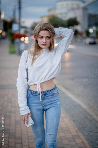 a girl in a white sweater is walking around the city