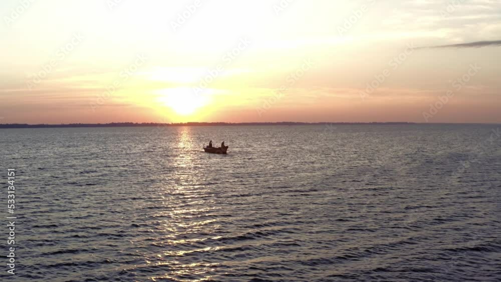 Aerial view of one motorboat in a large river. Beautiful sunrise and blue water. Silhouette Fisherman. Aerial view of one motorboat in a large river. Beautiful sunrise and blue water. Silhouette Fisherman.