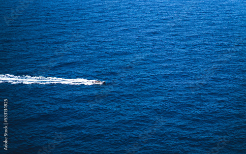Speed boat racing through the blue sea, leaving a white wake behind it © rory