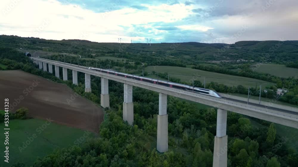 Passenger train crossing the railway flyover and entering the tunnel near La Roche-Sur-Grane (Drome - France). Overlooking the wind farm on the hill Passenger train crossing the railway flyover and entering the tunnel near La Roche-Sur-Grane (Drome - France). Overlooking the wind farm on the hill