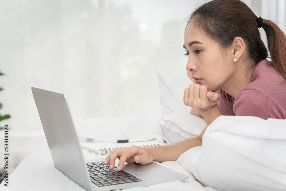Asian woman sitting at home working in the bedroom take notes of the meeting Record work with a notebook. Cheerful, fun at work. Asian woman sitting at home working in the bedroom take notes of the meeting Record work with a notebook. Cheerful, fun at work.