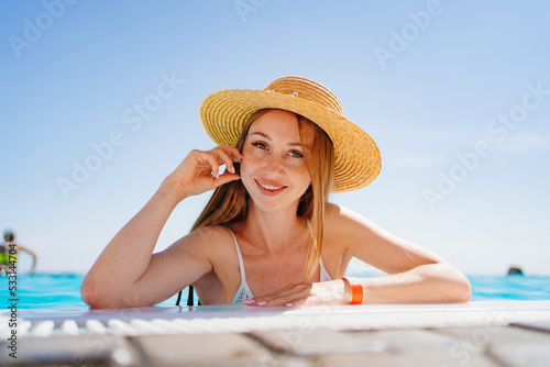 portrait of a happy woman with eyes closed in a hat at the side of the pool