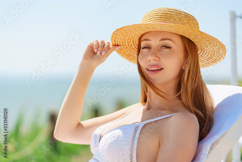 Papier peint a beautiful woman in a straw hat sunbathing on a chaise longue on a beach