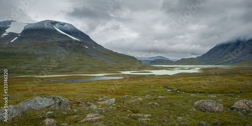 Lake under the moutains in remote arctic valley on cloudy day of arctic summer. Pierikjaure or Bierikjavrre lake, Sarek National Park, Lapland, Sweden. Hiking in wilderness of Laponia. Rain in arctic.