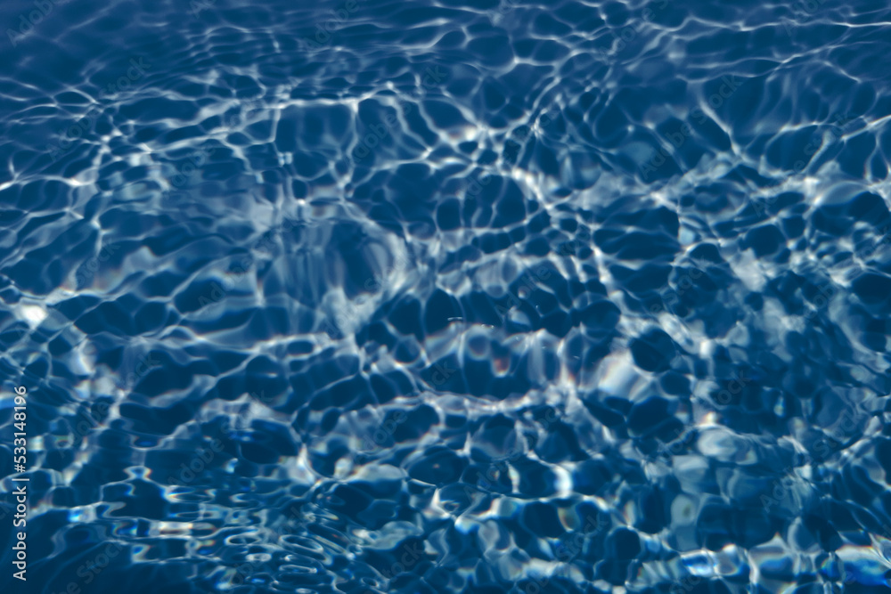 Defocus blurred transparent blue colored clear calm water surface texture with splash, bubble. Shining blue water ripple background. Surface of water in swimming pool. Blue bubble water shining.