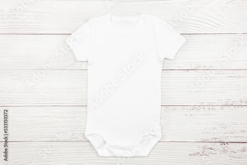 White baby girl or boy bodysuit mockup flat lay on wooden background. Design onesie template, print presentation mock up. Top view.