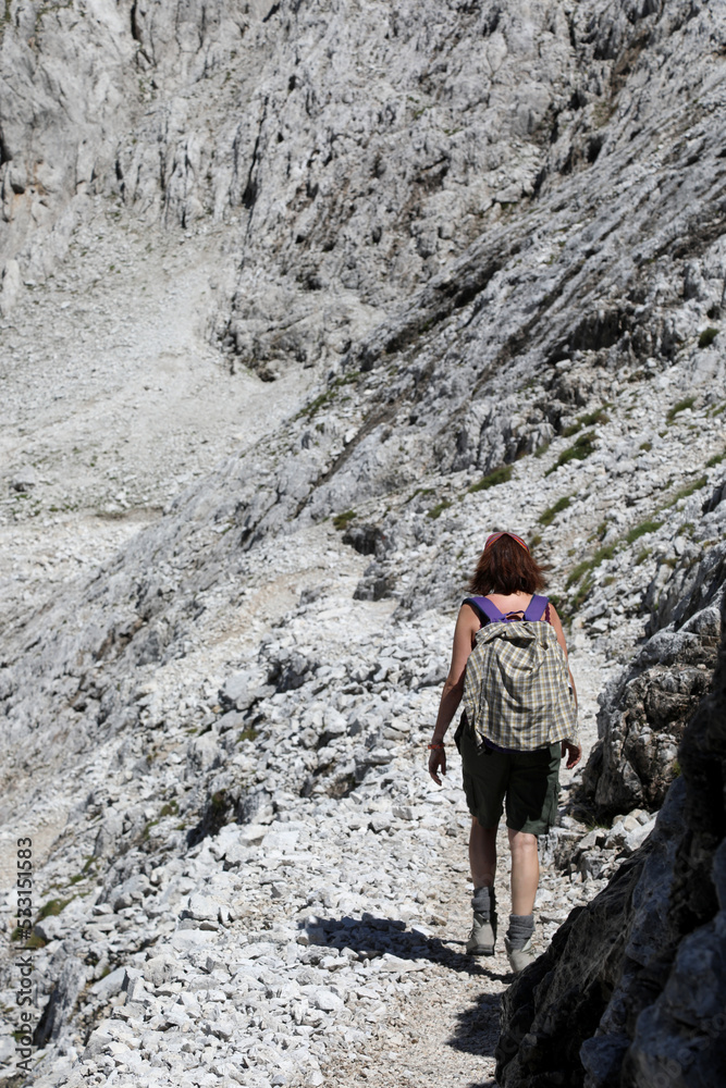 Young woman walks on the trail of the Dolomites in the European Alps called Pale Group  in Italy