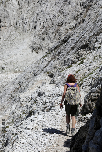 Young woman walks on the trail of the Dolomites in the European Alps called Pale Group in Italy
