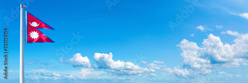 Nepal flag waving on a blue sky in beautiful clouds - Horizontal banner