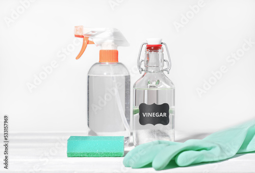 white vinegar for home cleaning chores, natural householding detergent, affordable product for housekeeping, rubber glove and kitchen sponge next to sprayer bottle.