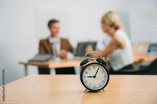 Workplace with alarm clock in modern style on background business meeting