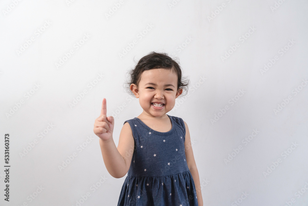 Happy smiling Asian child girl posing and pointing up isolated on white background. Happy smiling Asian child girl posing and pointing up isolated on white background.