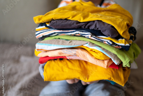 boy holding a stack of clothes. Kids clothing fashion.