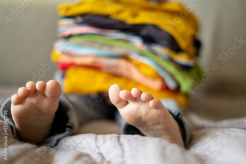 boy holding a stack of clothes. Kids clothing fashion.