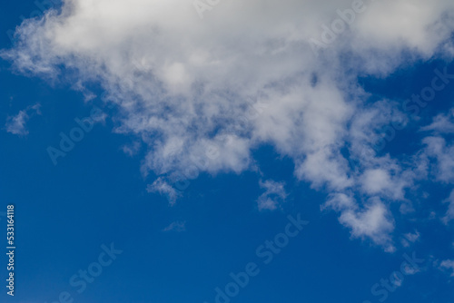 Weiße flauschige Wolken vor dunkelblauem Himmel bei Tageslicht an einem Tag im Sommer als Zeichen für Freiheit