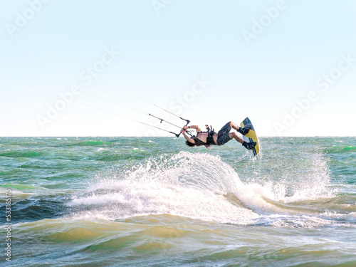 Young man kite boarder jumps over the sea at sunset. Selective focus.