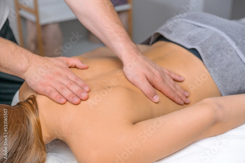 Male strong hands massage the woman's back. Body care, cosmetic procedures, relaxation day.
