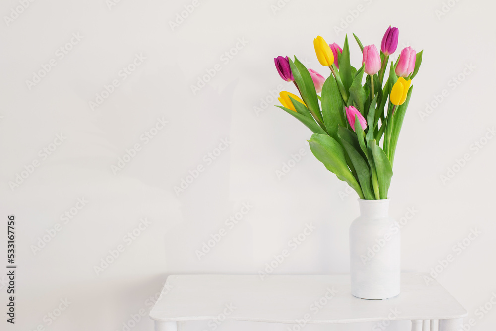tulips in white vase on wooden shelf on white background tulips in white vase on wooden shelf on white background
