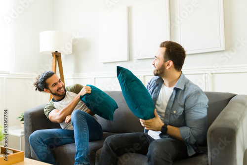 Fun gay couple having a pillow fight game in the living room