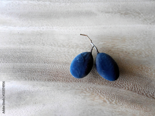 Close up of Black Velvet tamarind plum (Dialium cochinchinense) on the wooden table, Thai folk name Lookyee, sour and sweet taste when ripe with black peels. photo