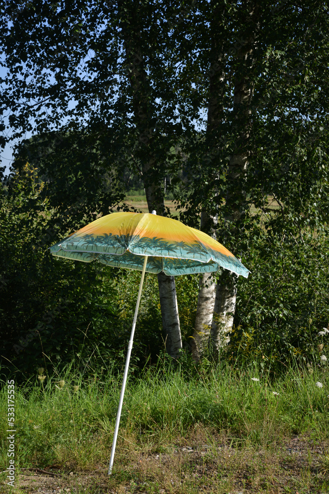 colorful parasol stuck in the ground by the side of the road.