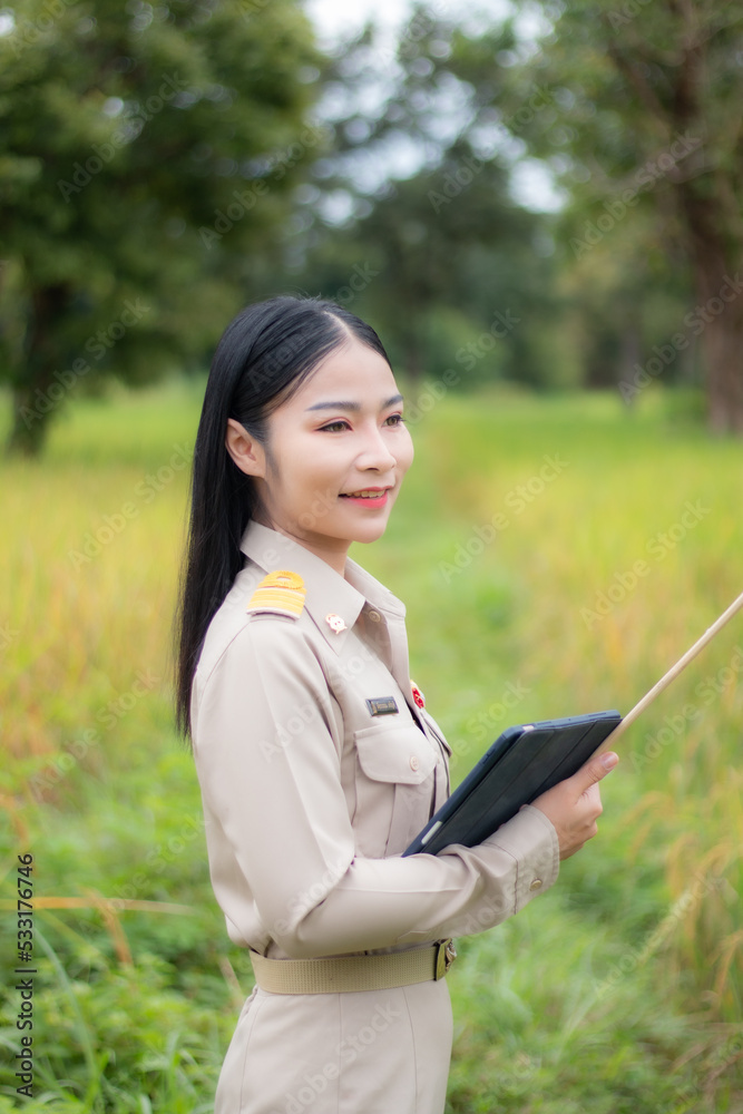 Beautiful Thai teacher with a tablet computer in rice filed. Beautiful Thai teacher with a tablet computer in rice filed.