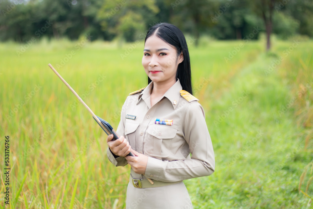 Beautiful Thai teacher with a tablet computer in rice filed. Beautiful Thai teacher with a tablet computer in rice filed.